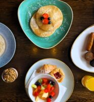 A luxurious breakfast spread at Louis Fitzgerald Hotel featuring pancakes, a cooked breakfast, and fresh fruits.