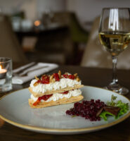 Elegant dessert with whipped cream and berries, paired with white wine on a candle-lit table.