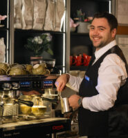 Smiling barista makes coffee at Louis Fitzgerald Hotel.