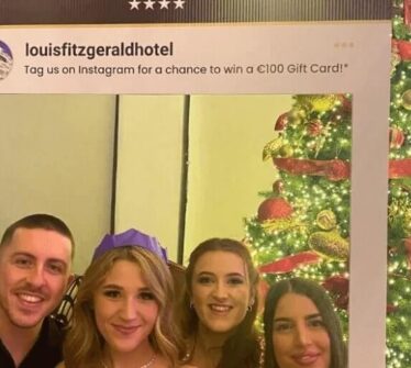 Group celebrating at a festive event with Christmas decor at Louis Fitzgerald Hotel.
