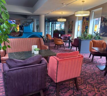 Welcoming hotel lounge with vibrant chairs and cosy seating, featuring colourful artwork.
