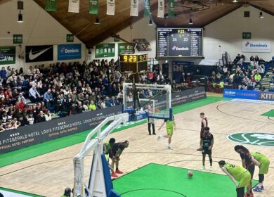 Basketball game with spectators, Louis Fitzgerald Hotel signage visible.