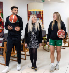 Hotel guests enjoying a conversation in the stylish lobby, holding basketballs.