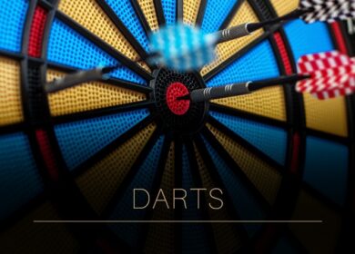 Close-up of a dartboard with three darts hitting the bullseye. Text reads “DARTS”.