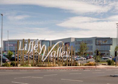 Entrance sign for Liffey Valley Shopping Centre, Dublin with parked cars in the background.