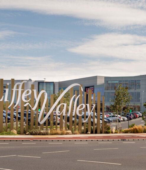 Entrance sign for Liffey Valley Shopping Centre, Dublin with parked cars in the background.