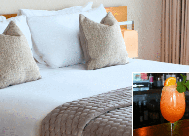 Elegant hotel room with plush bedding and a refreshing cocktail on a bar counter.