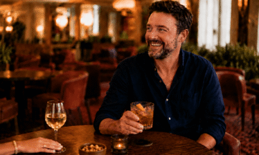 Man enjoying a drink in a cosy hotel bar with warm lighting.