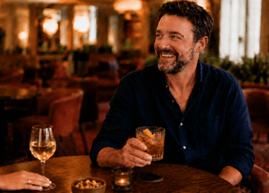 Man enjoying a drink in a cosy hotel bar with warm lighting.