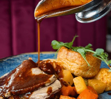 Succulent roast beef with gravy, served with Yorkshire pudding and roasted vegetables.