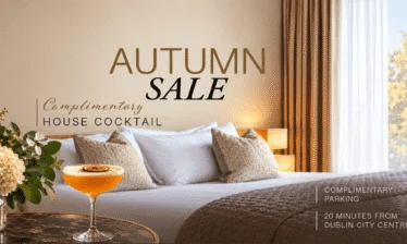 Elegant hotel room with king bed, autumn leaves view, and cocktail on the table.