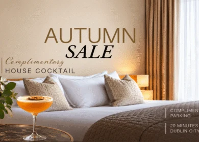 Elegant hotel room with king bed, autumn leaves view, and cocktail on the table.