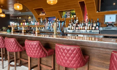 Stylish hotel bar with red leather stools and a well-stocked selection of drinks.