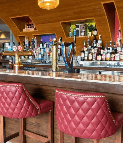 Stylish hotel bar with red leather stools and a well-stocked selection of drinks.
