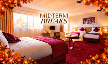 Spacious hotel family room with three beds, warm autumn décor, "MIDTERM BREAKS" text visible